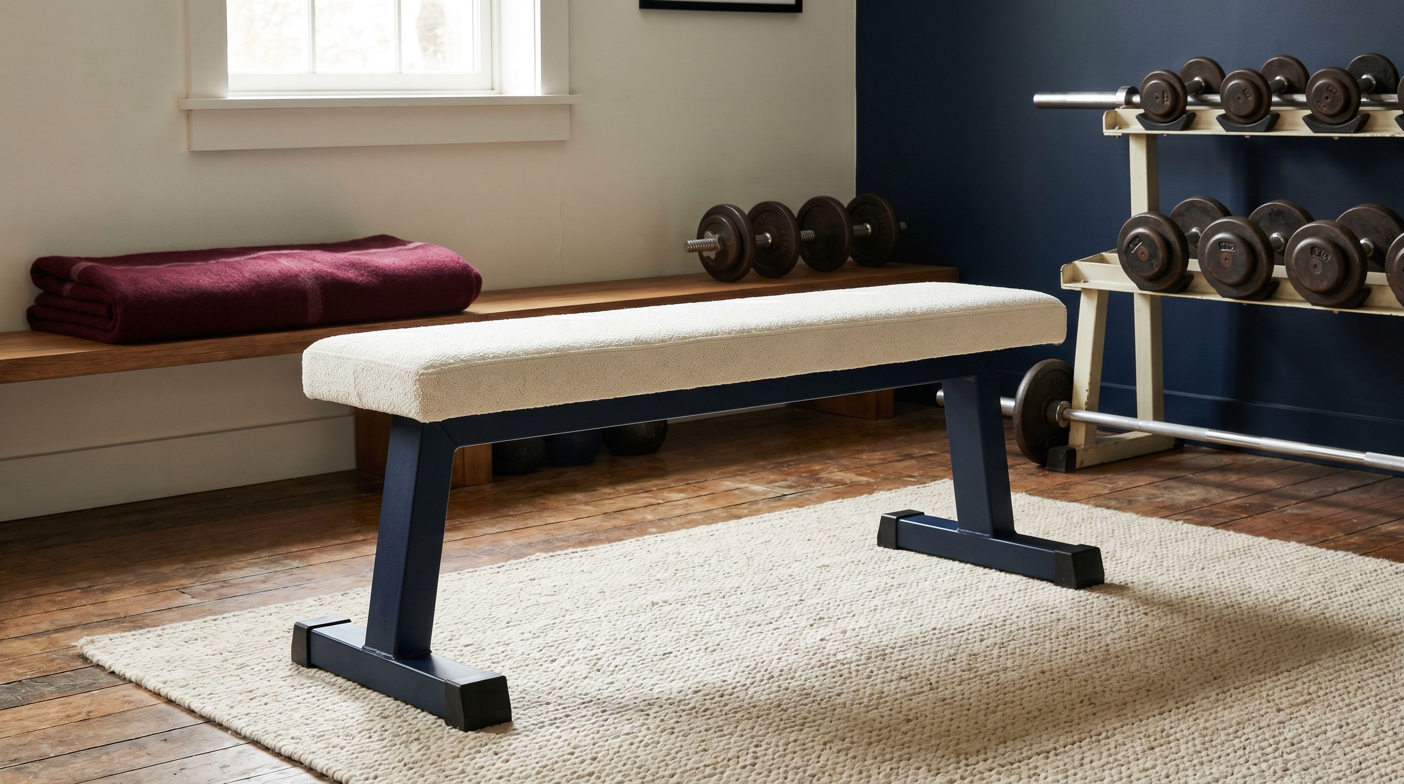 Banc de musculation en home-gym — vue plate studio sur fond off-white
